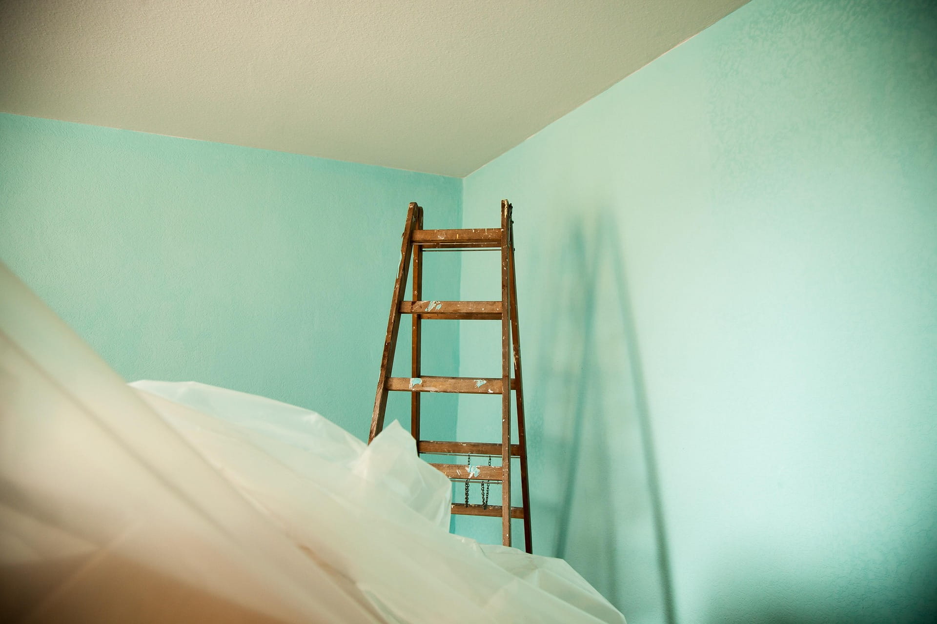 Quarto residencial pintado em verde menta com escada e proteção de piso
